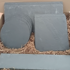 Pack de platos y bandejas de pizarra natural en diferentes formatos presentados en caja, ideales para servir aperitivos, carnes y postres